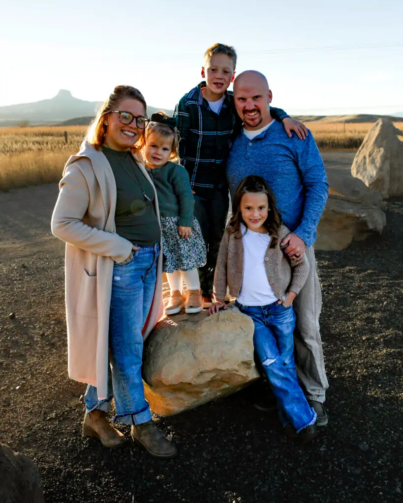 Family standing together outdoors in a Wyoming landscape with mountains at sunset