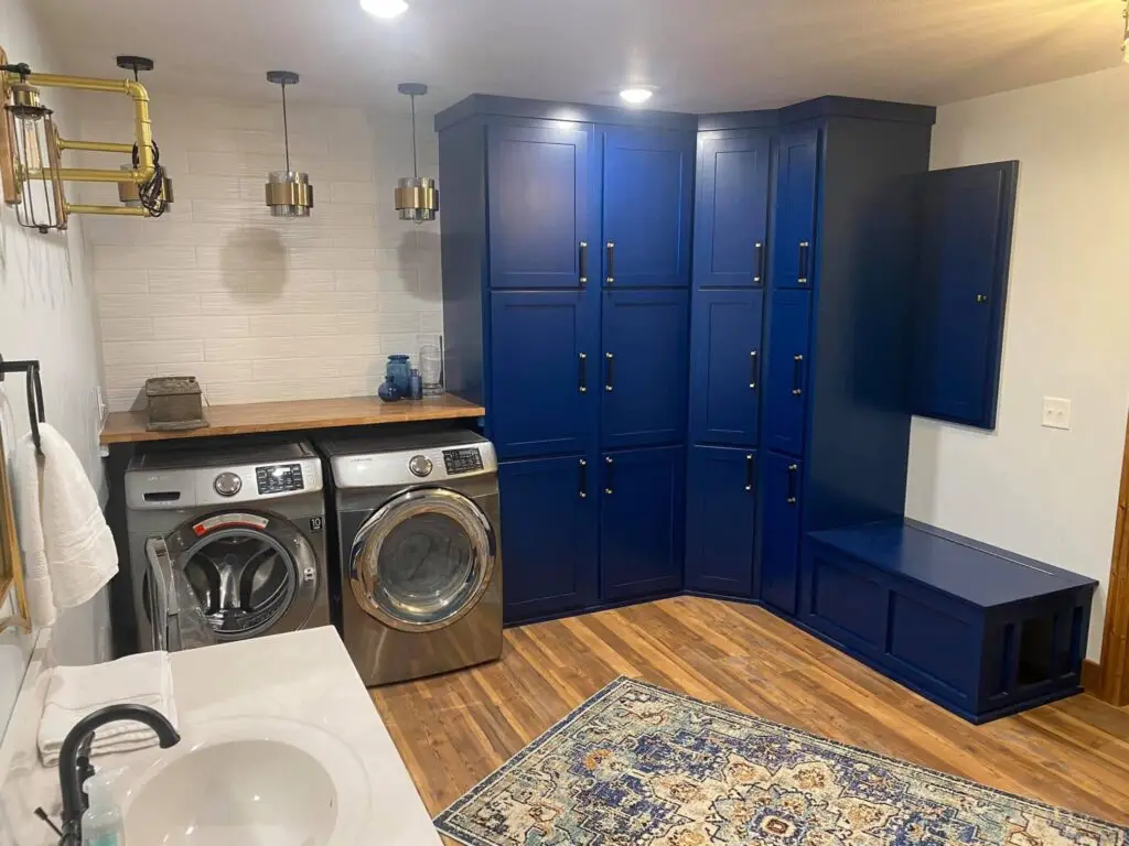 Custom laundry and mudroom with blue built-in cabinets, wood countertop, and modern washer and dryer